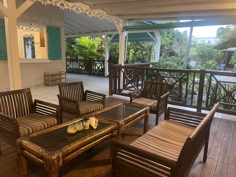 Salon extérieur en bois sur la terrasse couverte de la villa
