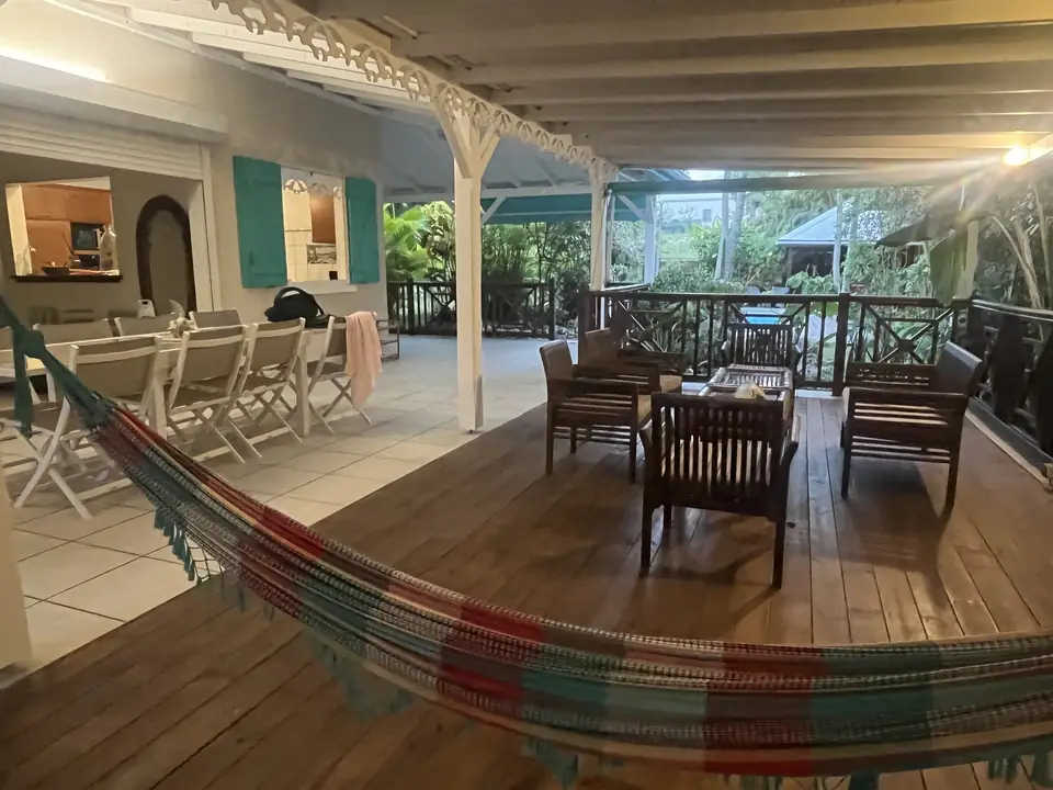 Grande terrasse couverte de la villa avec table à manger et hamac